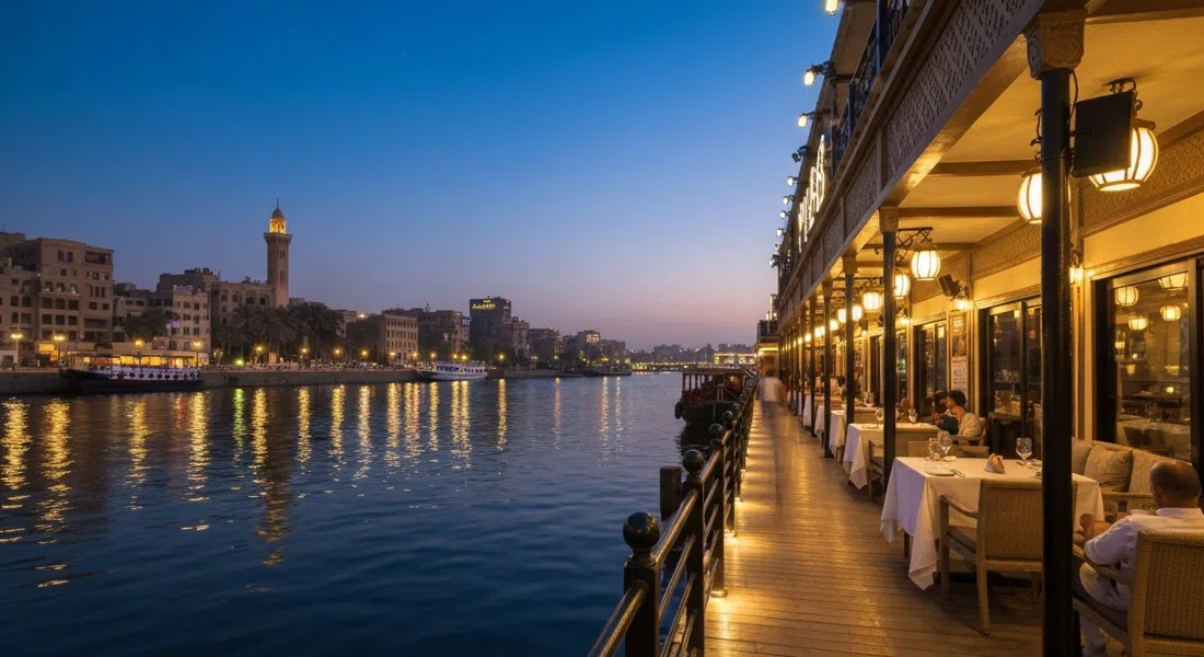 Pier88 Nile River a bordo del Imperial Boat amarrado al anochecer, luces de la terraza reflejadas en el Nilo y una mesa de alta cocina colocada junto al agua